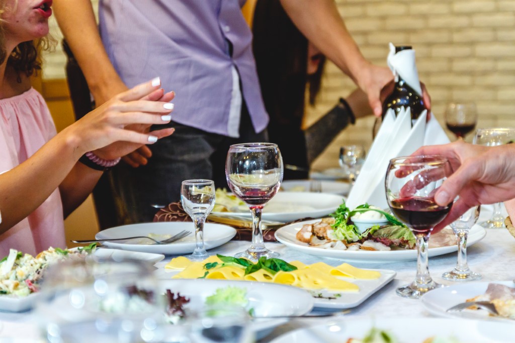 People Communicate At A Festive Table With Food And Glasses In A